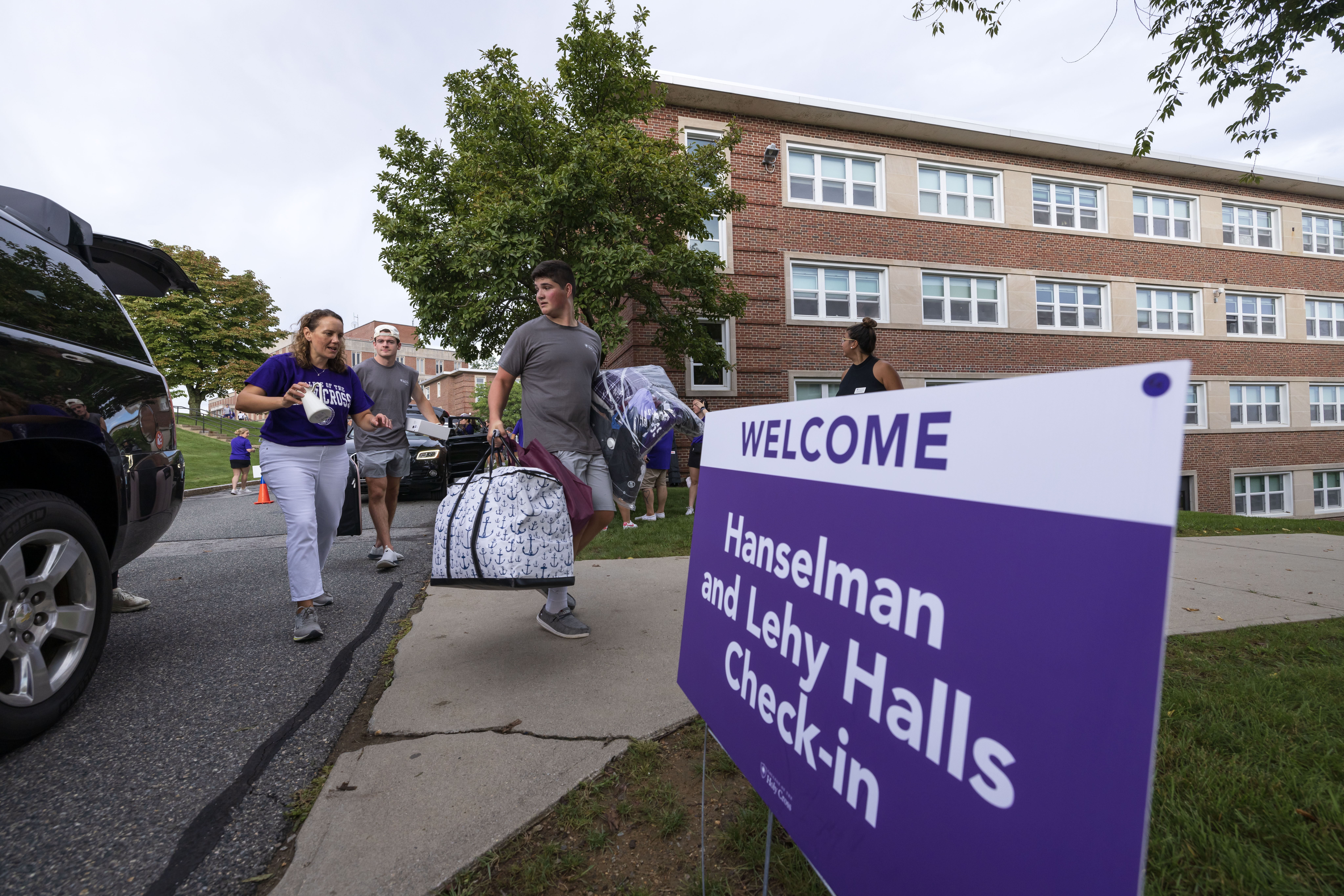 Students approaching a dorm with bags
