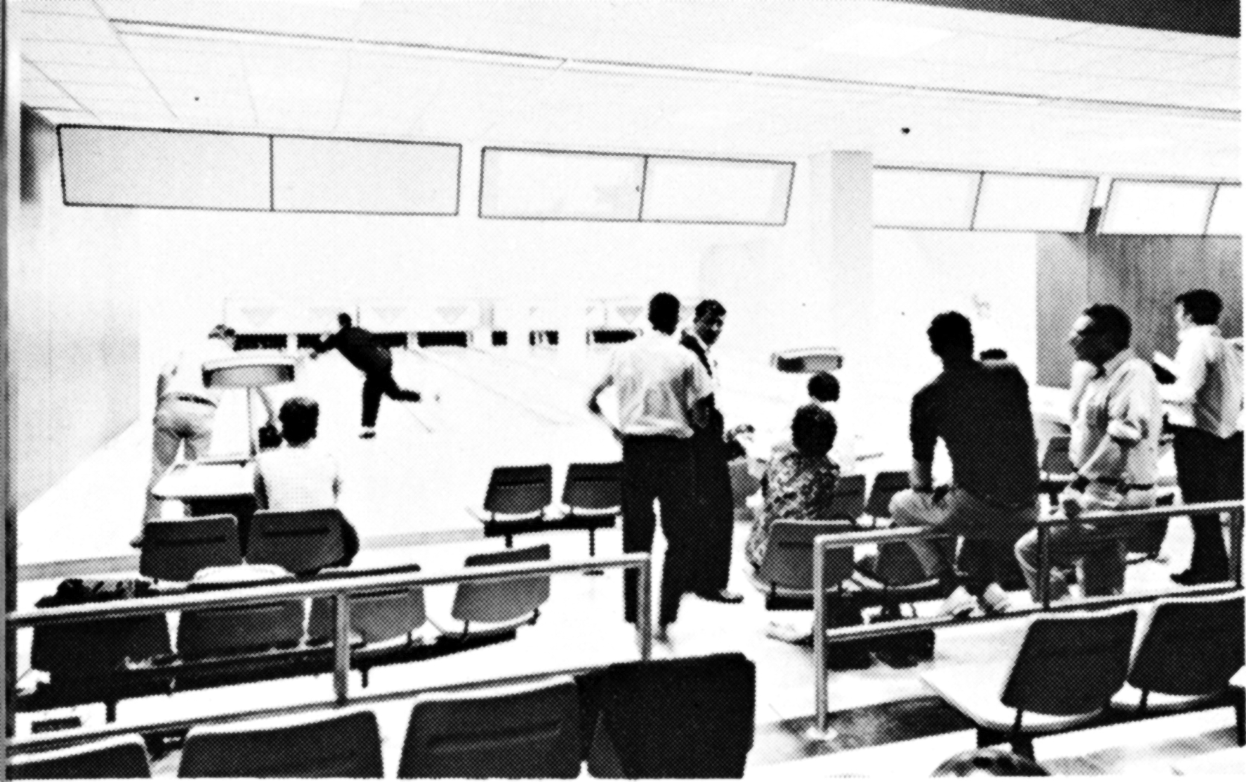 Folks standing, sitting and participating at a bowling alley