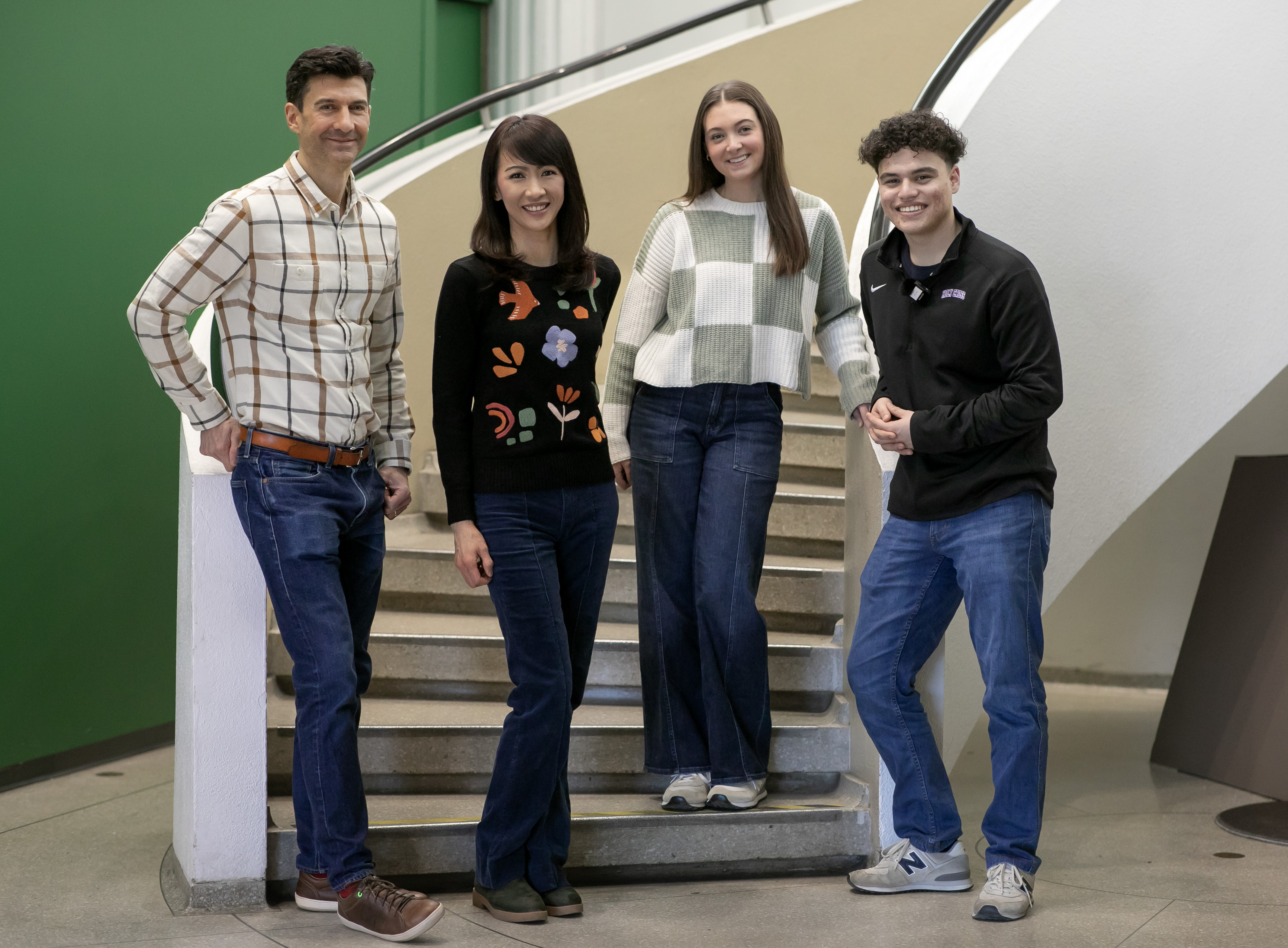 Four people - two professors and two students - post on a staircase.