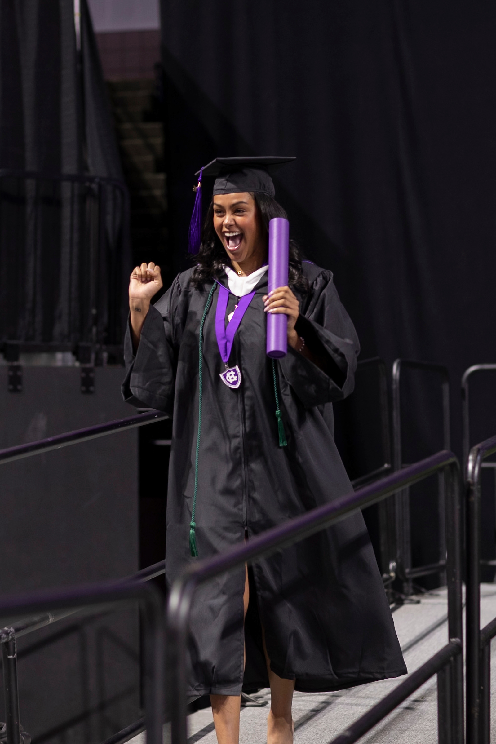 Female student who just graduated college cheers after she receives her diploma.