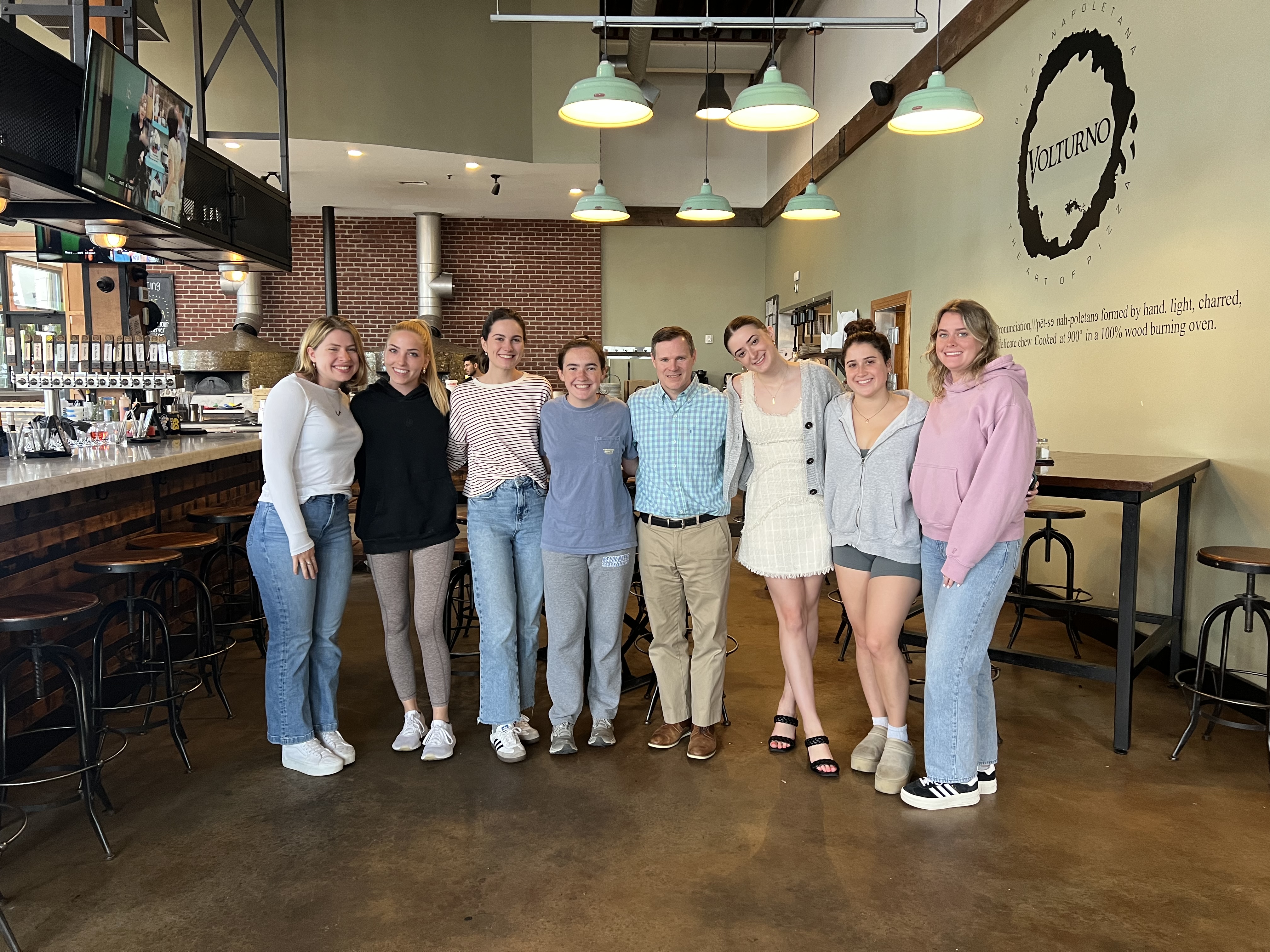 Several young women standing in a line, posing for a picture at a restaurant in Worcester