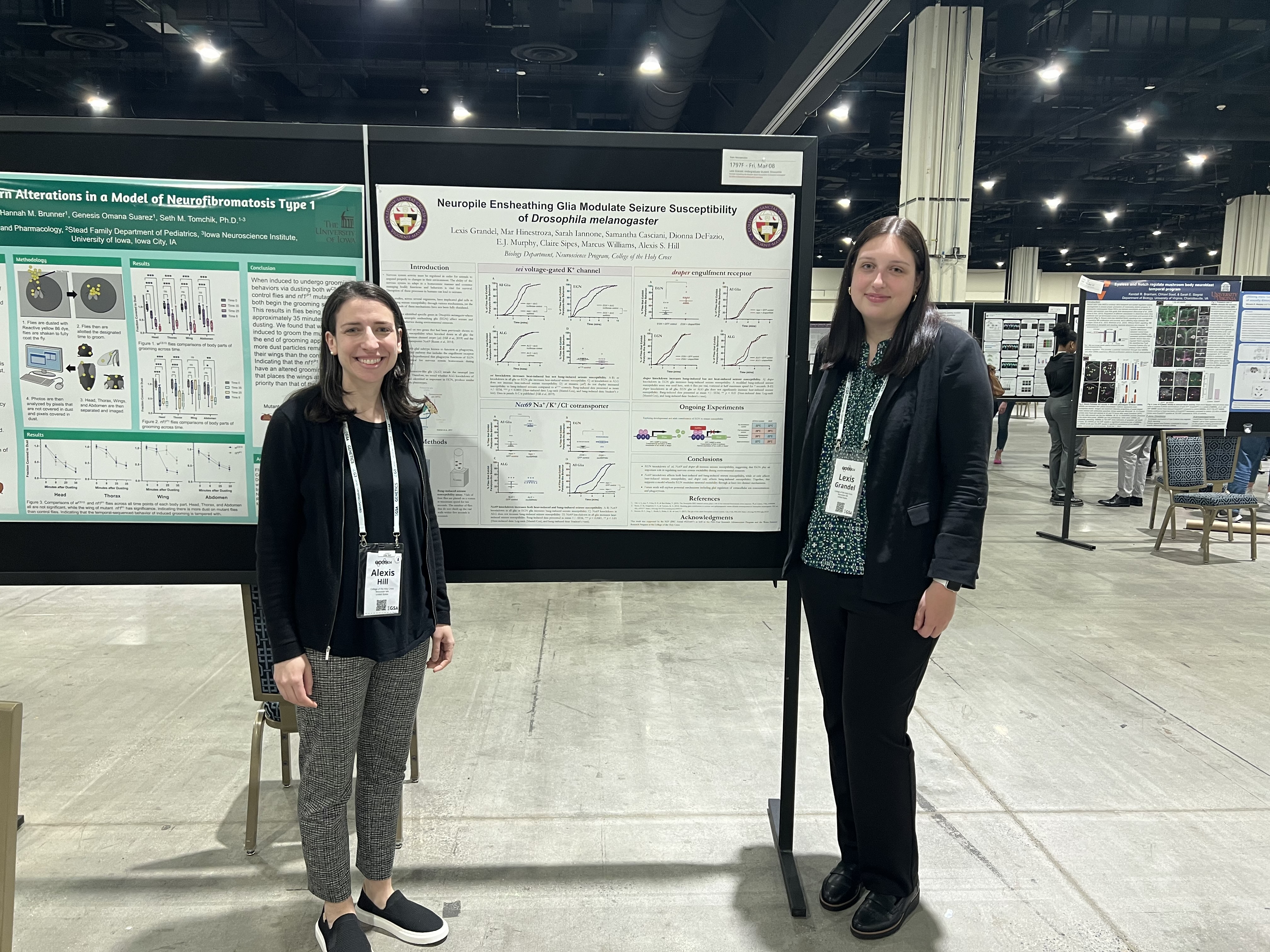 Professor and student at a conference poster presentation standing in front of a large board.