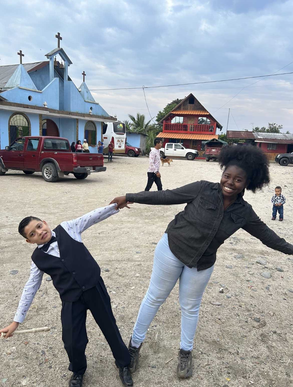 A young woman and a child hold hands while leaning away from each other