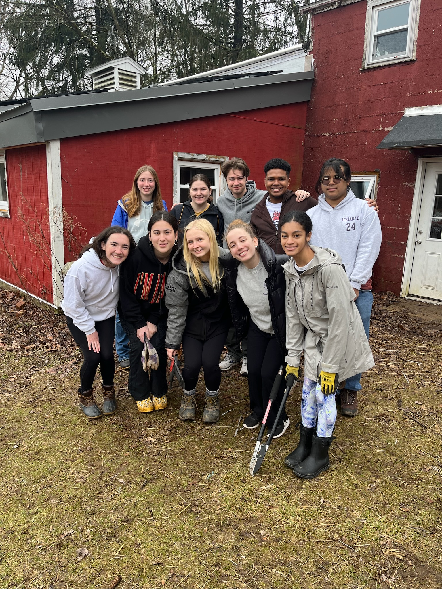 A group of young people posing in front of a red house