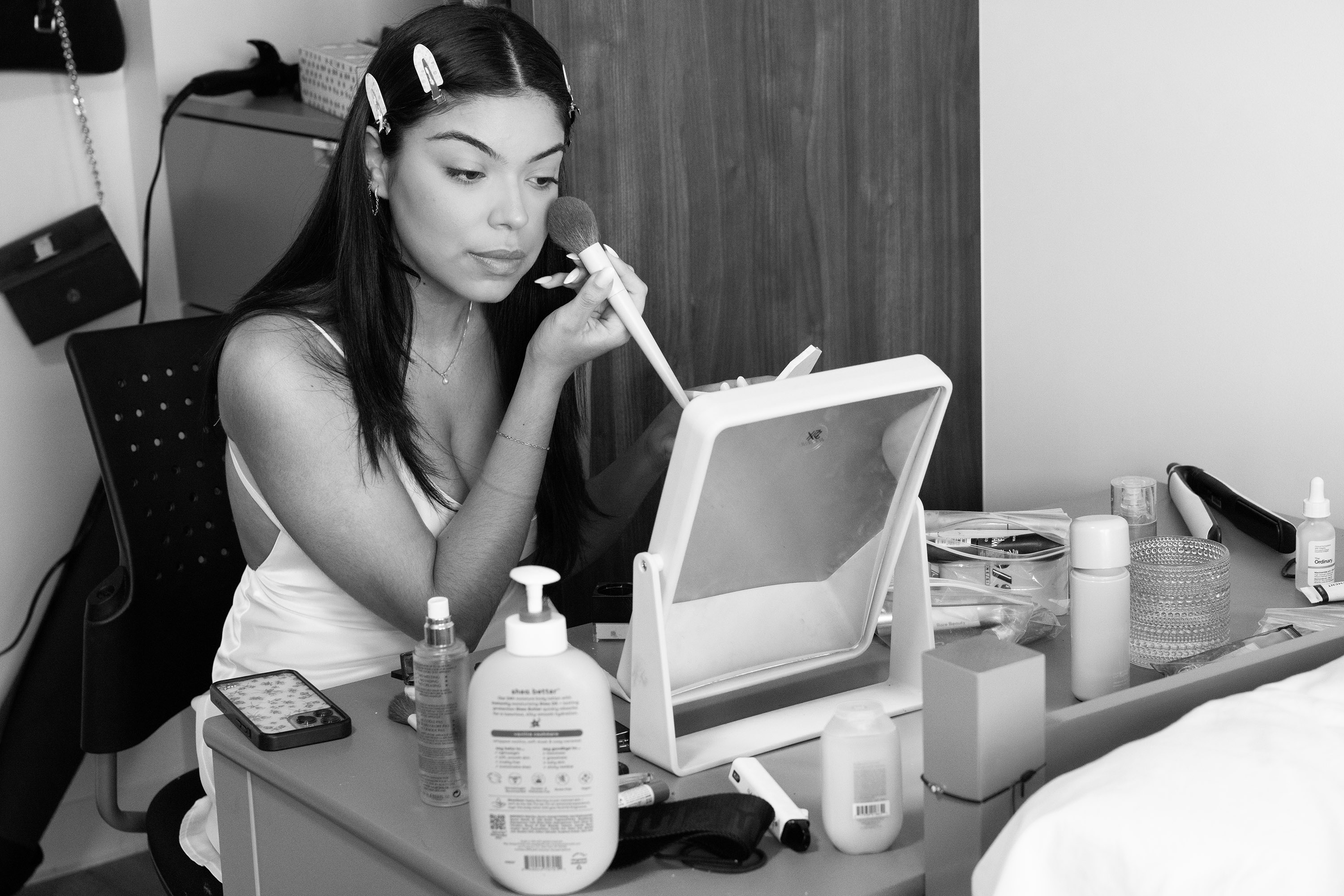 A woman applies makeup while looking in the mirror