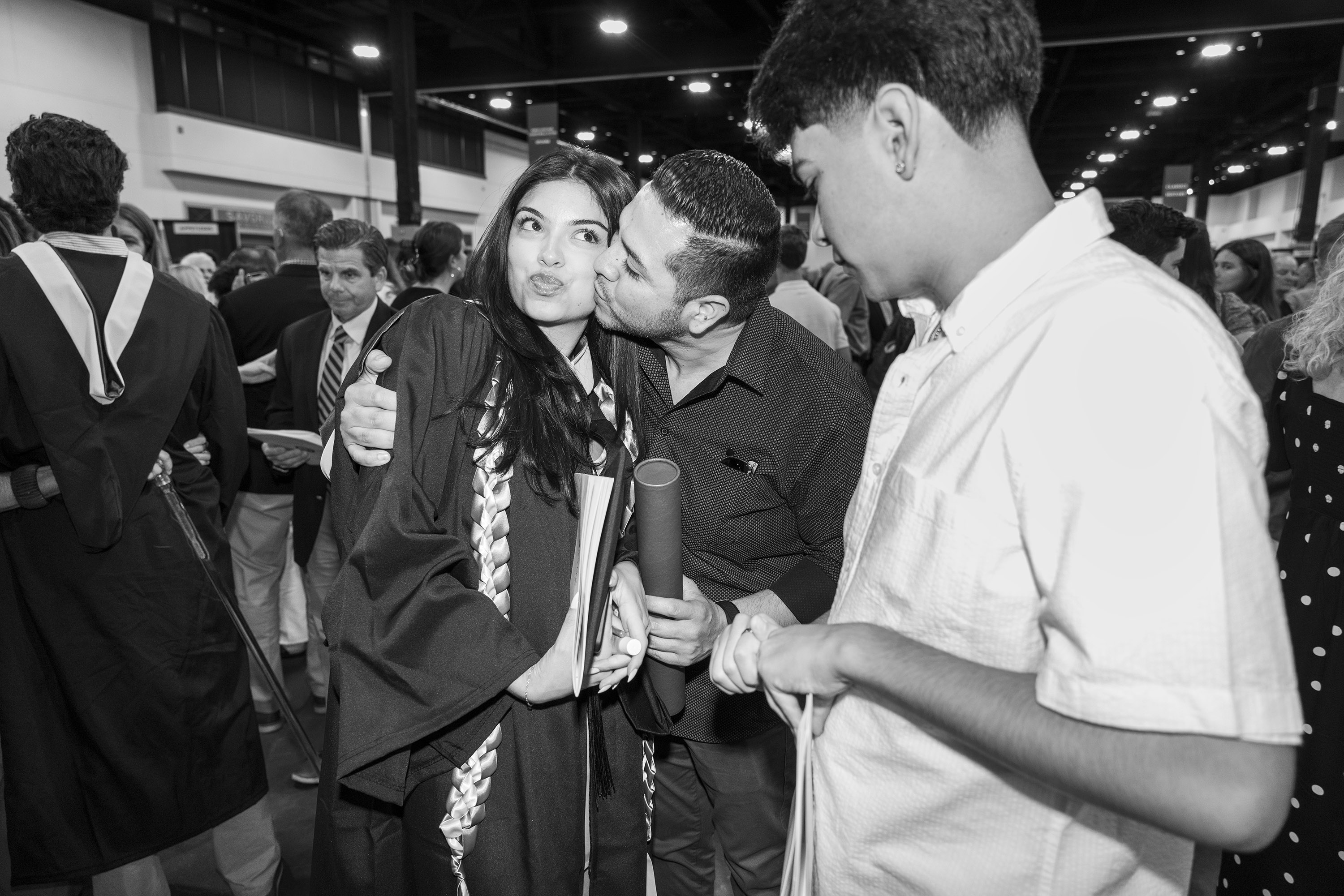 A graduate gets a kiss fro her dad after commencement