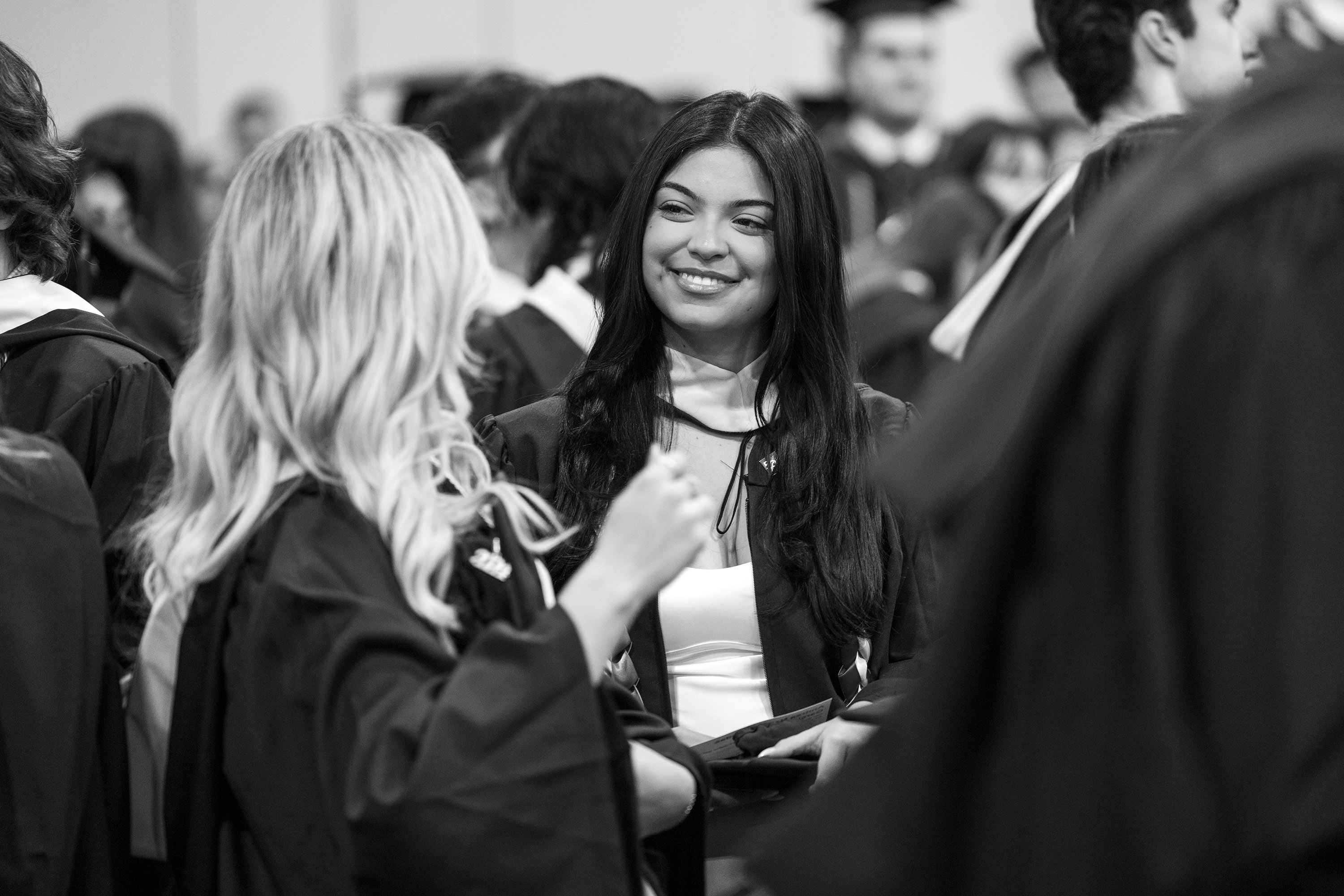 A graduate smiles at her friend backstage