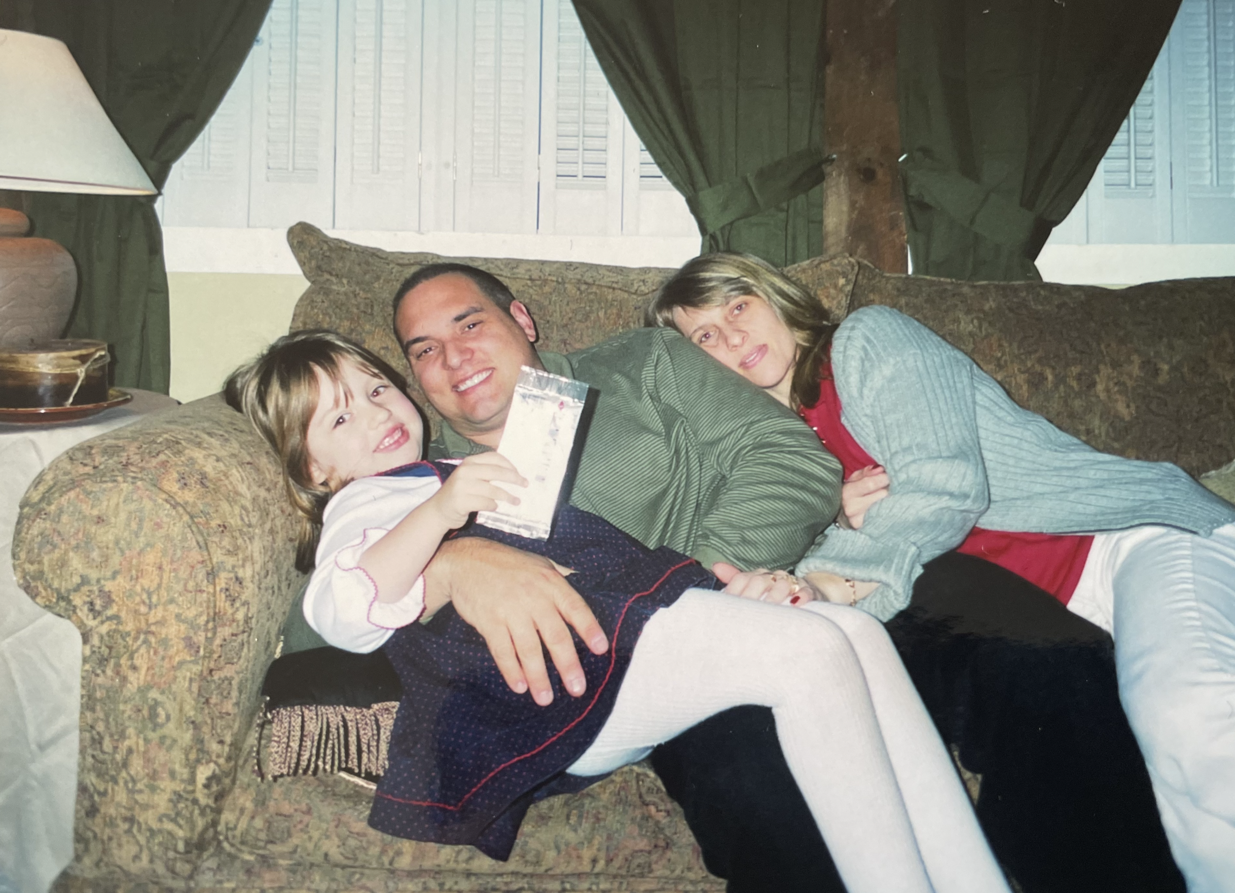 Mother, father and daughter cuddling on the couch.
