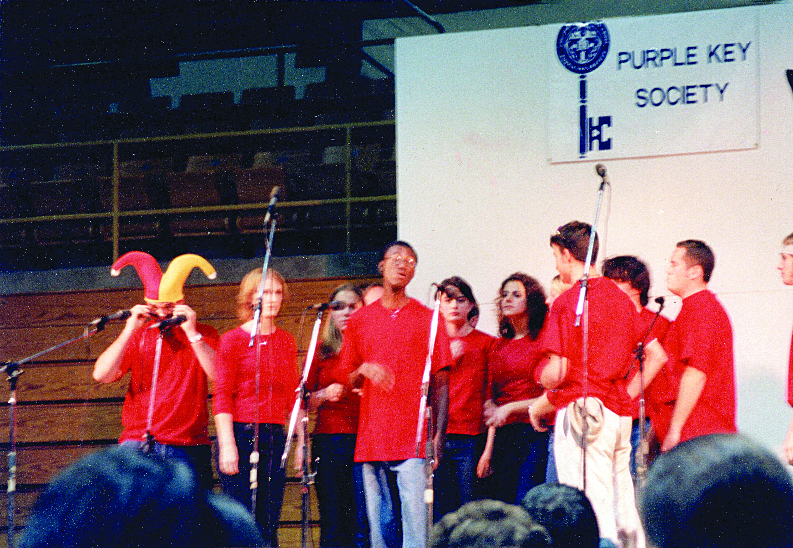 A group of students in the same uniform singing on a stage