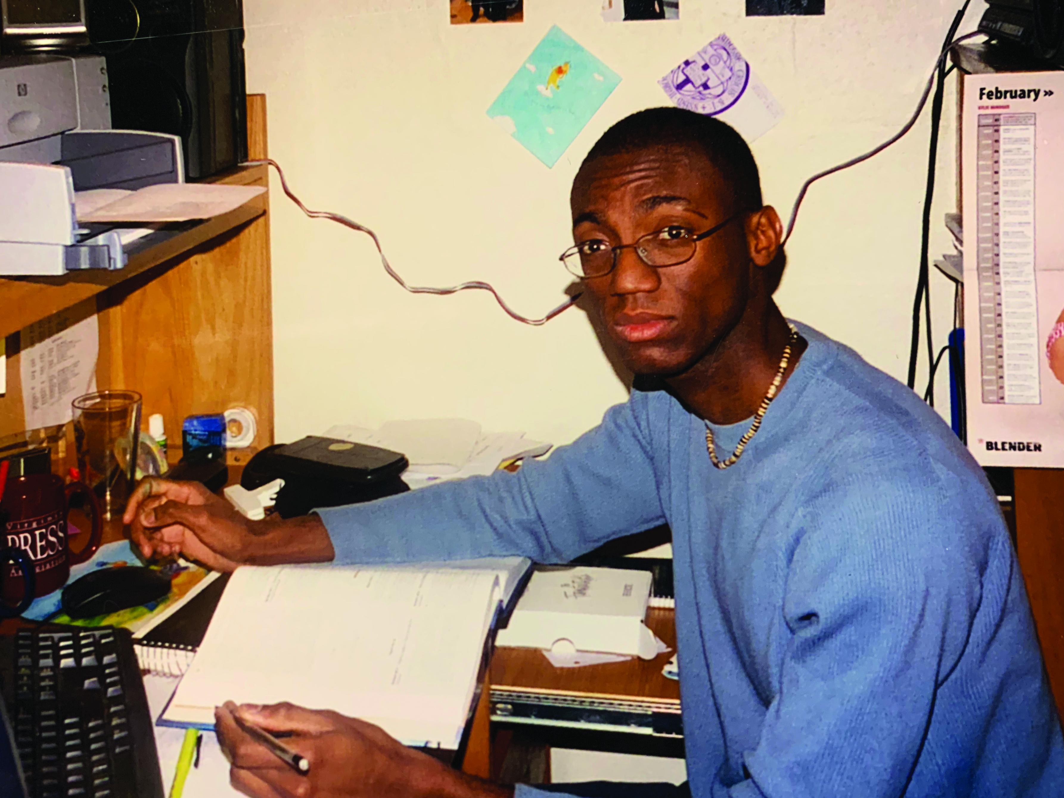 André Isaacs sitting at a desk in a resident hall with a book in front of him