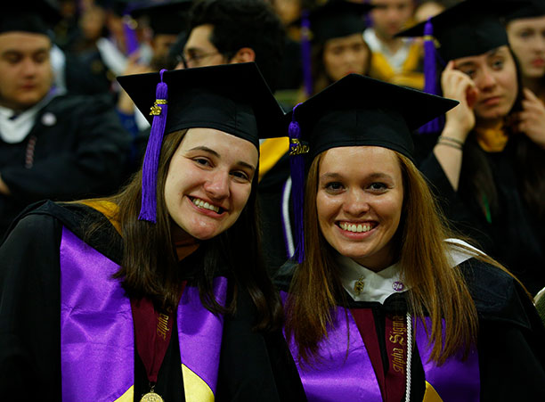 Two students take a break from the commencement ceremony for a quick photo.