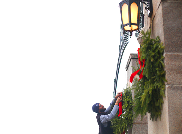 Grounds staff member adorn the College’s main gates with wreaths.