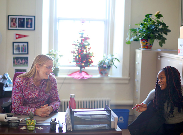 Jan Lenahan, administrative assistant of the political science department, talks with Jewel Duberry-Douglas '18 in her decorated office.