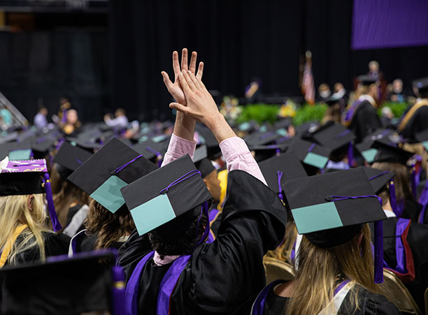 A student cheers for a friend crossing the commencement stage.