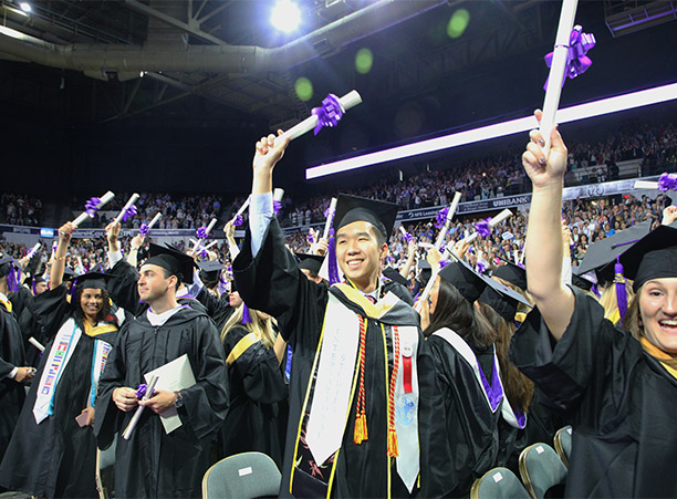 A student waves while holding their diploma.