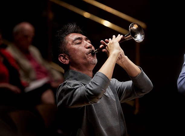 A man plays a trumpet-like instrument