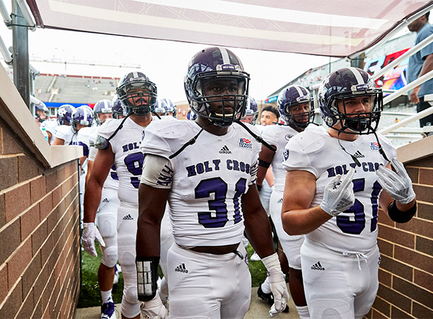 holy cross football players walk onto field