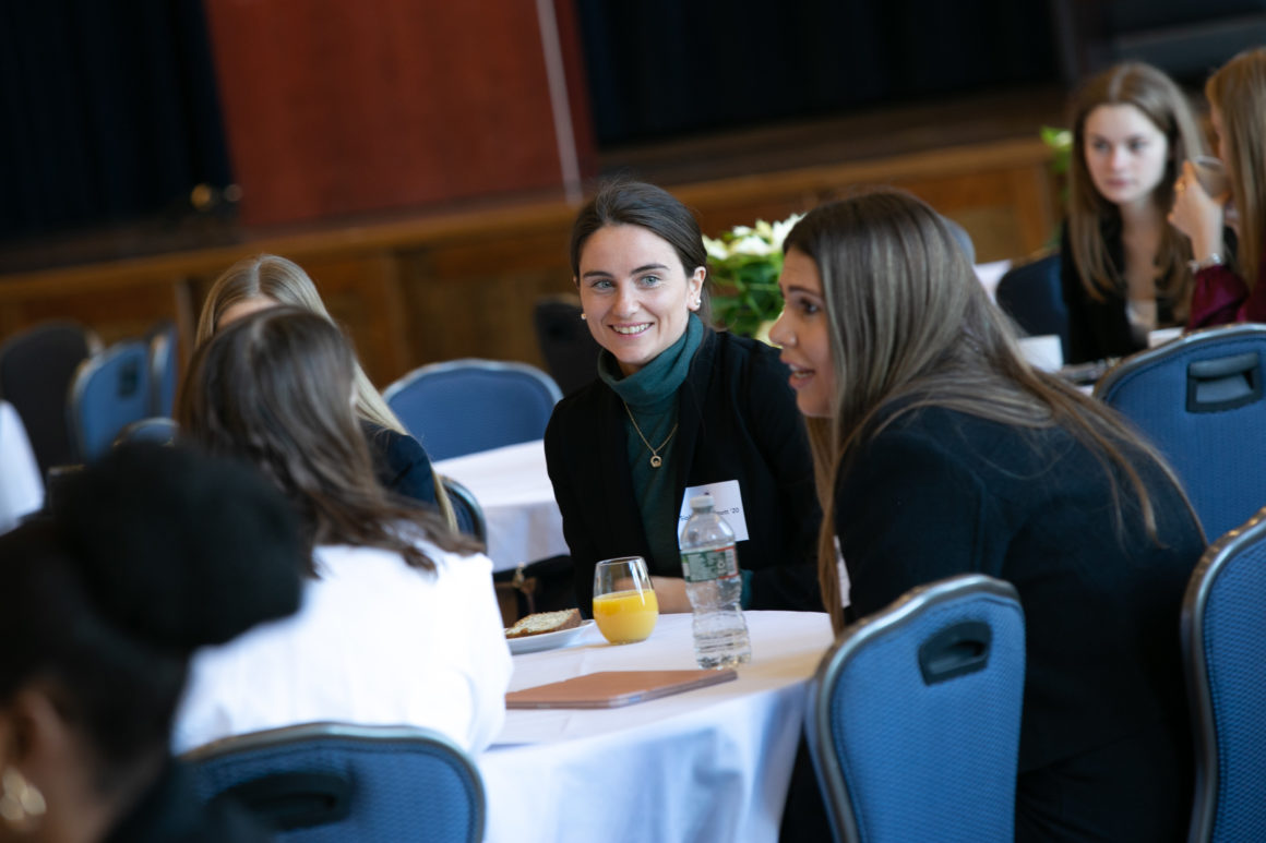 Three women sit at a table talking