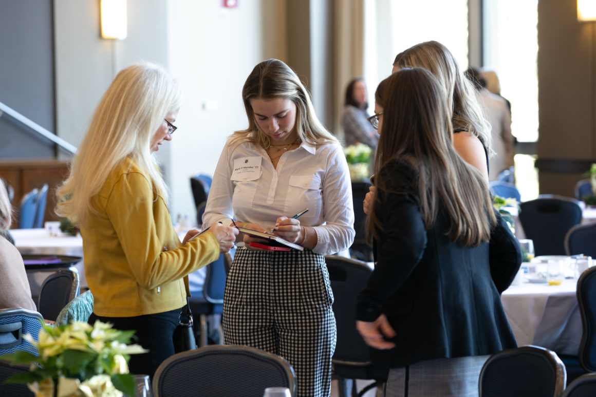 Women standing talking and exchanging written information.