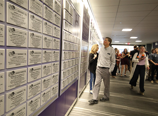 Attendees explore the Varsity Club Hall of Fame plaques lining a hallway of the athletic complex during the dedication celebrations.