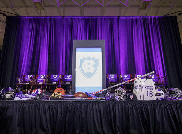 Set up in the basketball arena for the speaking program, the stage is decorated with equipment representing each of the College's 27 varsity athletic teams.