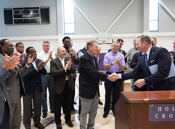 Former men's basketball coach George Blaney '61 shakes hands with Nate Pine, as family, friends and former basketball players gather for the blessing of the new auxiliary basketball and volleyball practice gymnasium, dedicated in his honor.