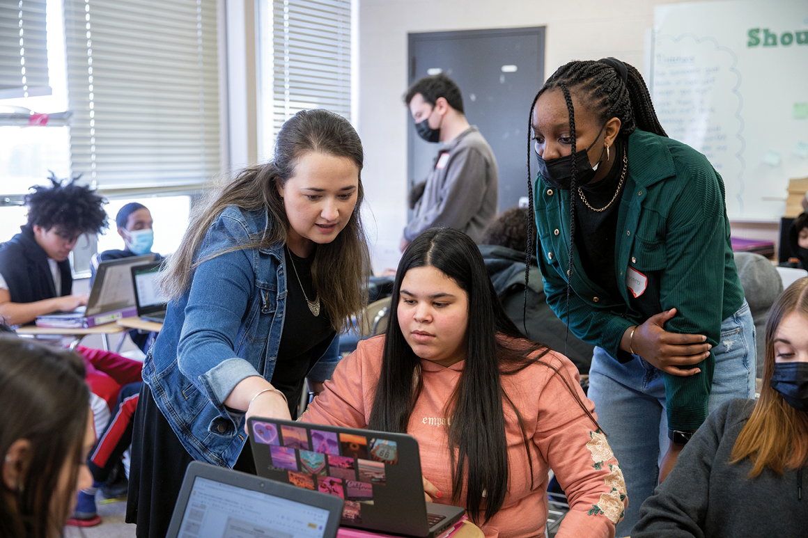 Lauren Delgado '16 working with a student in her English I class, while Holy Cross student Sanaea Simmons ’24 observes.