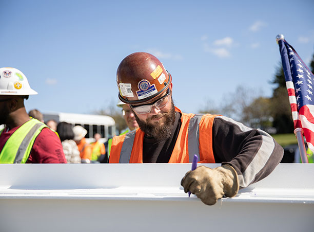 A construction worker signs the beam