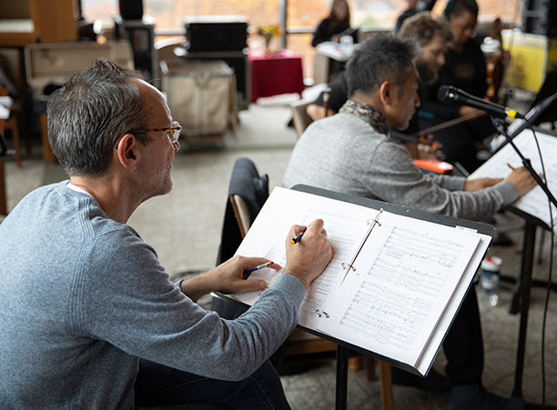 A man writes notes on a sheet of music