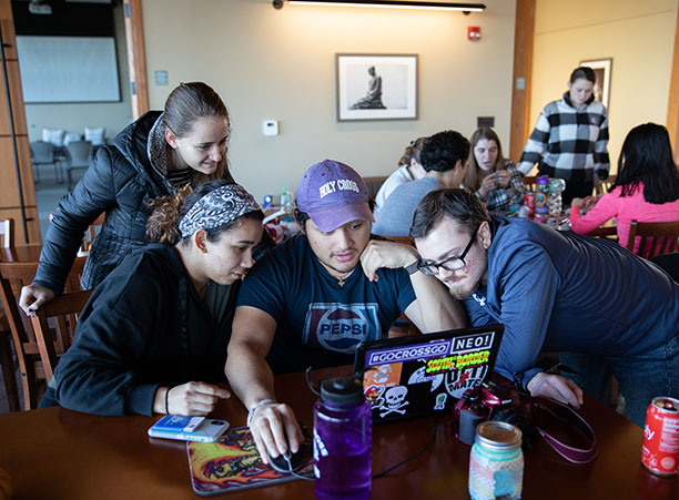 A group of students gather around a computer