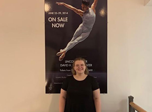 A student stands in front of a sign for the Boston Ballet