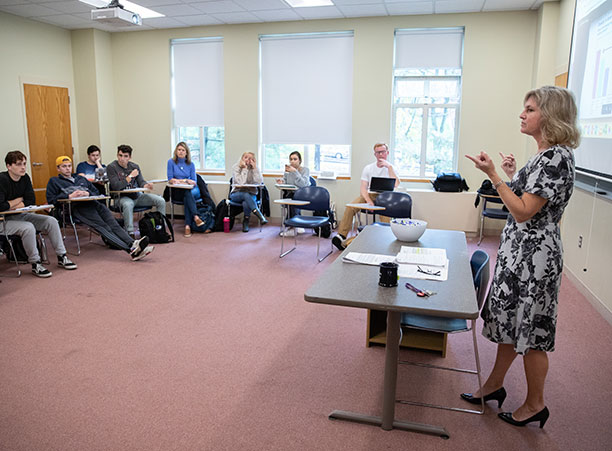 A group of students stand and sing while holding binders