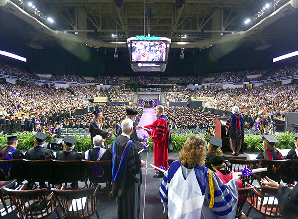 A student walks across the stage to receive their diploma from Rev. Philip L. Boroughs, S.J.