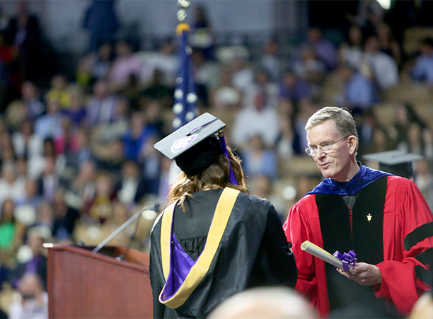 A student shakes the hand of Rev. Philip L. Boroughs, S.J. while receiving their diploma.