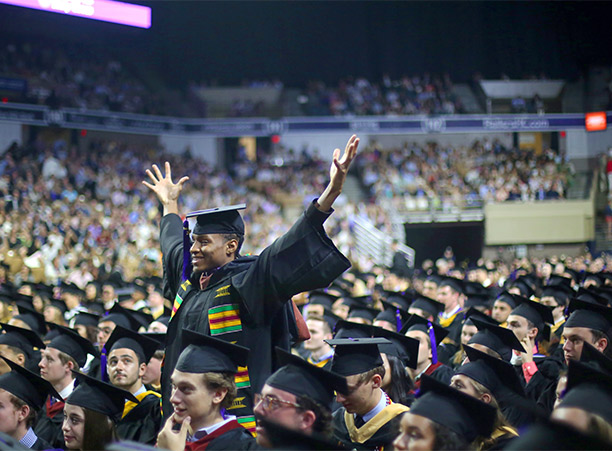 A student stands up and celebrates during the commencement ceremony.