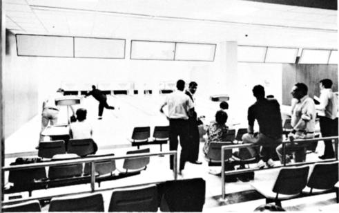 Folks standing, sitting and participating at a bowling alley