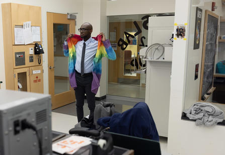 A science professor puts on a rainbow tie dye lab coat