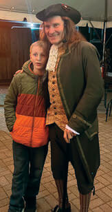 Man in 18th century clothing poses with a young boy.