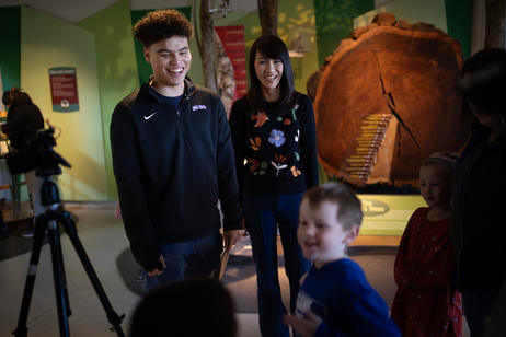 Male student and female professor laugh with a small boy at a museum.