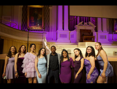 A group mostly young women and one young man pose for a picture in elegant attire