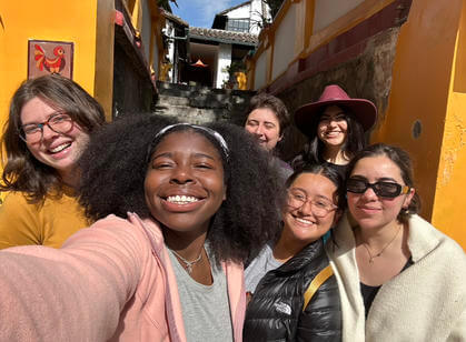 A group of friends huddled together smile while taking a selfie
