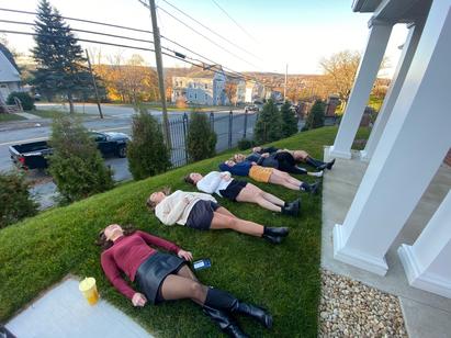 Several young women lying down in grass with the sun setting in the background