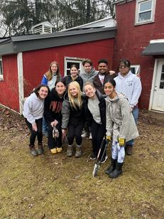 A group of young people posing in front of a red house