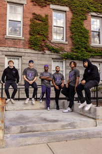A group of young men sitting on a railing outside a brick building