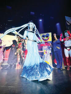 In a Halloween costume, a man looks like an alien with tentacles sprouting from his head and wearing a long skirt around his feet