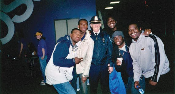 A group of smiling young men standing to the left and right of a police officer