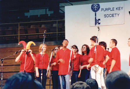 A group of students in the same uniform singing on a stage
