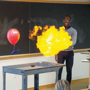A man performing a chemistry experiment causing a small ball of fire to appear in front of him