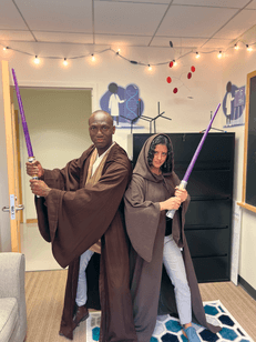 Two people dressed in robes, holding light sabers