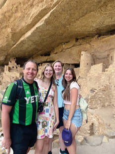 Four people stand near rock formation